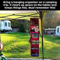 a woman sitting in a green chair under a tent next to a camper trailer