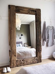 a mirror sitting on top of a wooden floor next to a bed