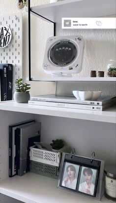 a white shelf with books and pictures on it