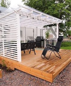 a wooden deck with chairs under a white pergolan