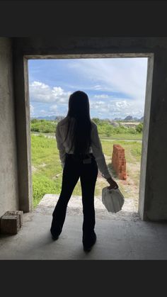 a woman standing in an open doorway with her back to the camera and holding a bag