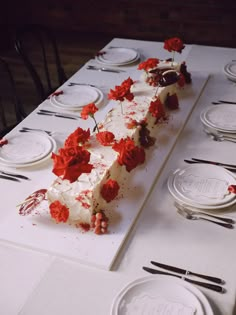 there is a long cake with red flowers on it