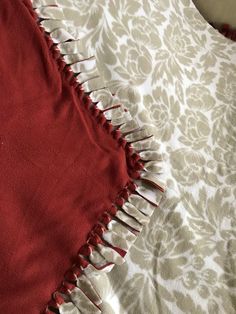 a red and white blanket on top of a bed next to a brown and white comforter