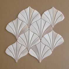 four white scallop shaped tiles sitting on top of a brown surface with lines drawn across them