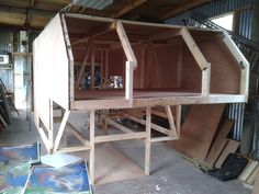 an unfinished wooden structure is being built in a garage with other woodworking tools and materials