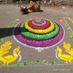 a colorful drawing on the ground next to a trash can