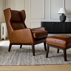 a brown leather chair and footstool in a living room with a rug on the floor