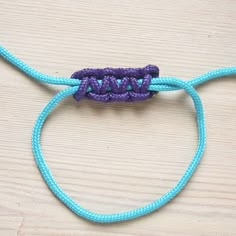 a piece of blue string with purple beads on it sitting on top of a wooden table