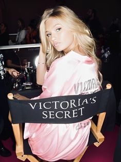 a woman sitting in a chair with a victoria's secret sign on her back