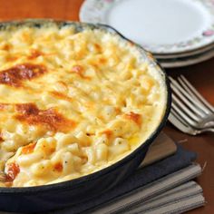 macaroni and cheese in a skillet on a wooden table with silverware