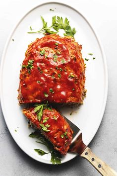 a white plate topped with meat covered in sauce and parsley