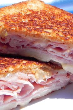 two grilled ham sandwiches sitting on top of a blue and white plate, one cut in half