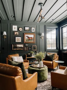 a living room with leather furniture and pictures on the wall above it's windows