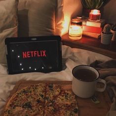 a pizza sitting on top of a wooden cutting board next to a cup of coffee