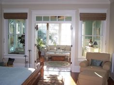 a living room filled with furniture and lots of windows next to a bed in a bedroom