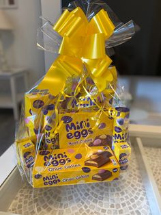 a basket filled with chocolates and candy bar wrapped in yellow ribbon on top of a table