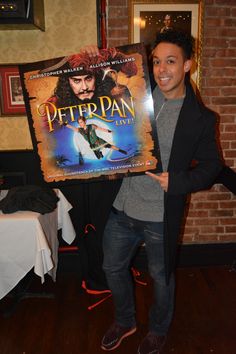 a man is holding up a poster for peter pan