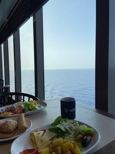 two plates of food on a table near the ocean