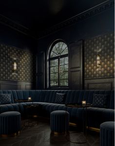 an empty room with blue velvet couches and round tables in front of a large window