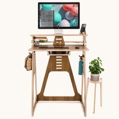 a computer monitor sitting on top of a wooden desk next to a potted plant