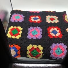 a crocheted granny blanket sitting on top of a chair with flowers in the center