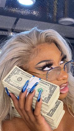 a woman in glasses holding money up to her face