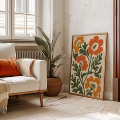 an orange and green floral print on a white wall next to a beige couch in a living room