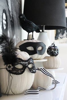 a table topped with white pumpkins and black masks