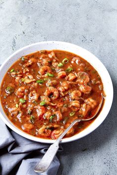 a white bowl filled with shrimp and red sauce on top of a blue table cloth