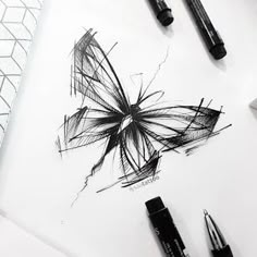 some pens are laying on top of a white paper with a butterfly drawn on it