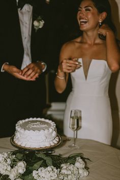 a man and woman standing next to each other in front of a cake