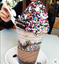 a woman taking a selfie with her cell phone while eating an ice cream sundae