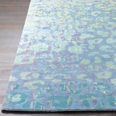 an area rug with blue, green and pink colors on it in a room that has wood floors