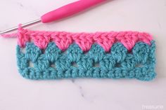 the crochet stitch is being worked on with a pink handled crochet hook