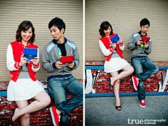 two people sitting on a brick wall holding electronic devices