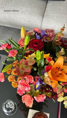 a bouquet of flowers sitting on top of a coffee table next to a vase filled with water