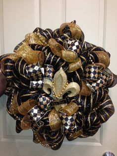 a close up of a wreath on a door with gold and black bows attached to it