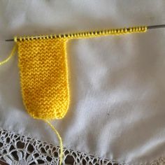 a close up of a yellow knitted object on a white cloth with crochet