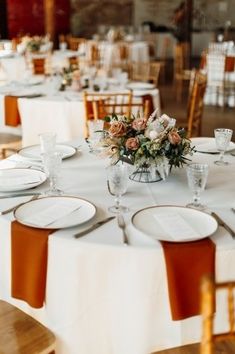 the table is set with white plates and place settings for guests to sit down at