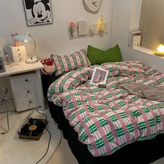 a bedroom with mickey mouse bedding and other items on the floor, including an alarm clock