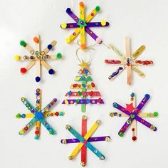 four popsicle christmas tree ornaments on a white surface with colorful beads and pins attached to them