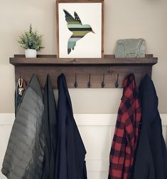 a coat rack with coats hanging on it and a potted plant next to it