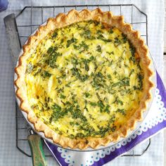 a quiche with spinach and cheese in a pie pan next to a knife