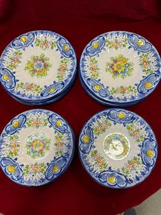 four blue and white plates sitting on top of a red cloth