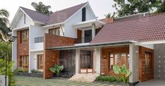 two story house with red tiled roof and white walls, surrounded by greenery in the front yard