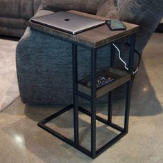 a laptop computer sitting on top of a small table in front of a gray couch