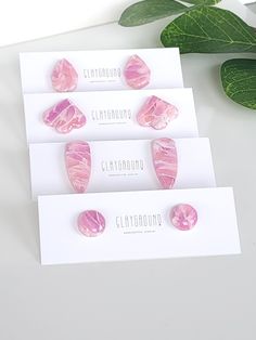 three pairs of pink earrings sitting next to each other on top of a white table