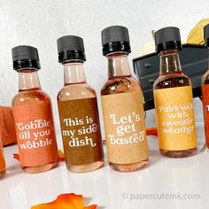 five bottles of different types of alcohol sitting on a white surface next to an orange flower