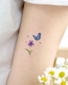 a woman's arm with flowers and a butterfly tattoo on the left side of her leg