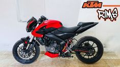 a red and black motorcycle parked in front of a white wall